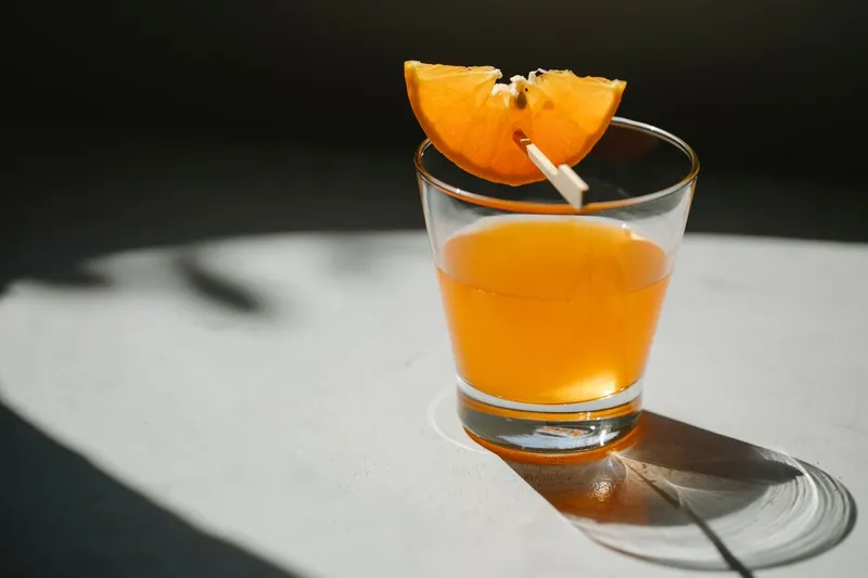 Cocktail orange dans un verre, garni d’une tranche d’agrume. Photographie d’inspiration.