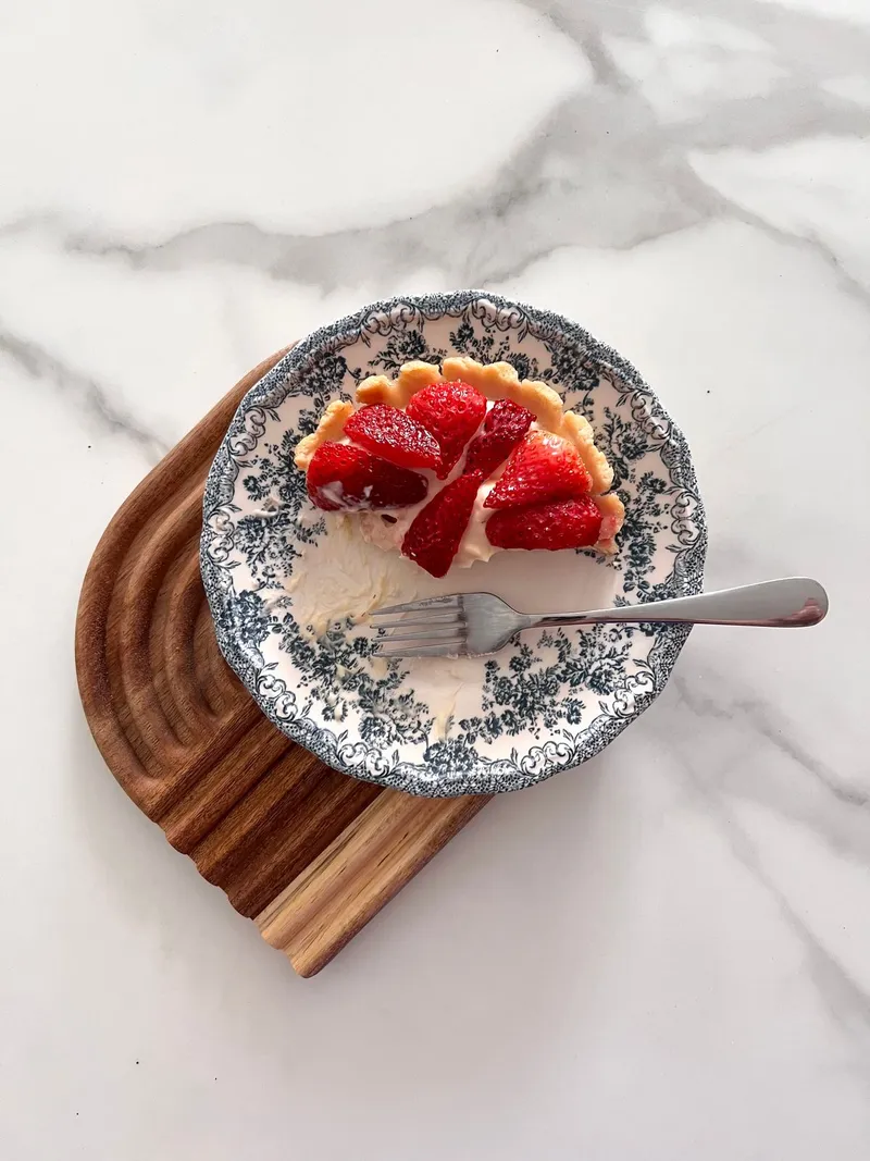 Tartelette aux fraises sur une assiette décorative. Photographie d’inspiration.