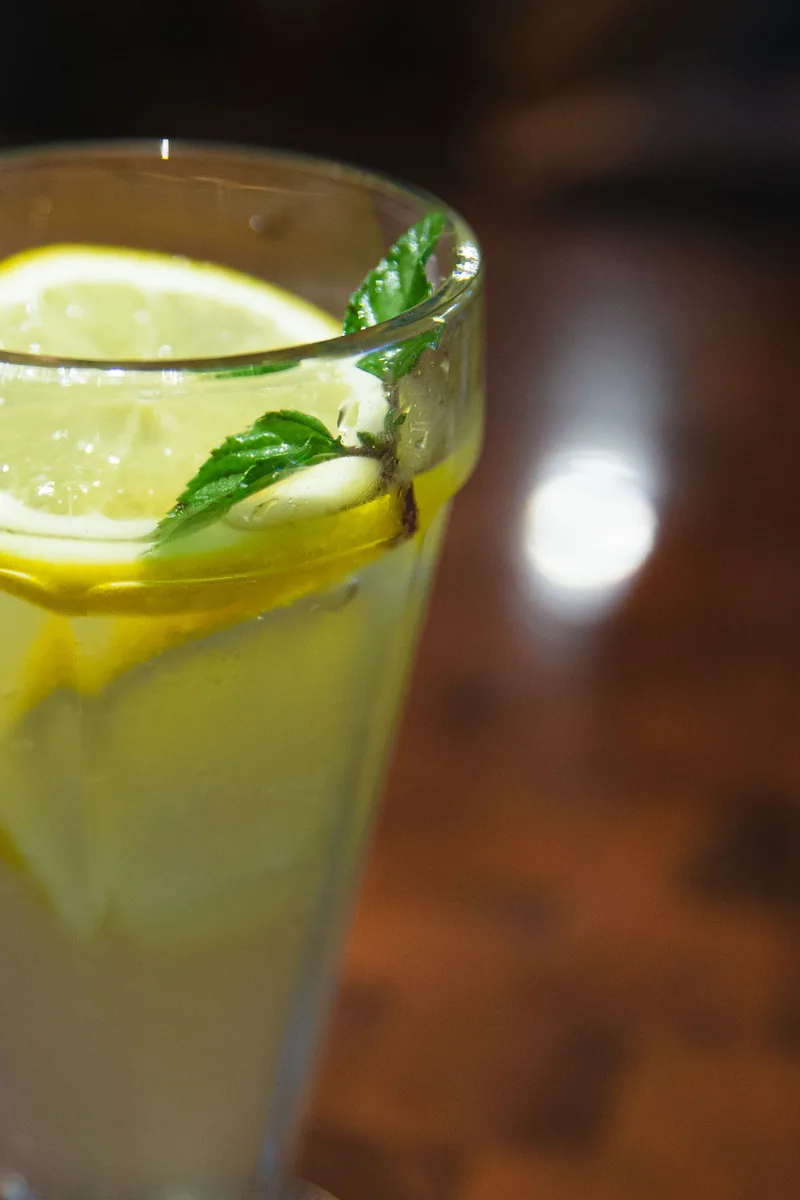 Citron et menthe dans un verre de limonade, en lumière naturelle. Photographie d’inspiration.