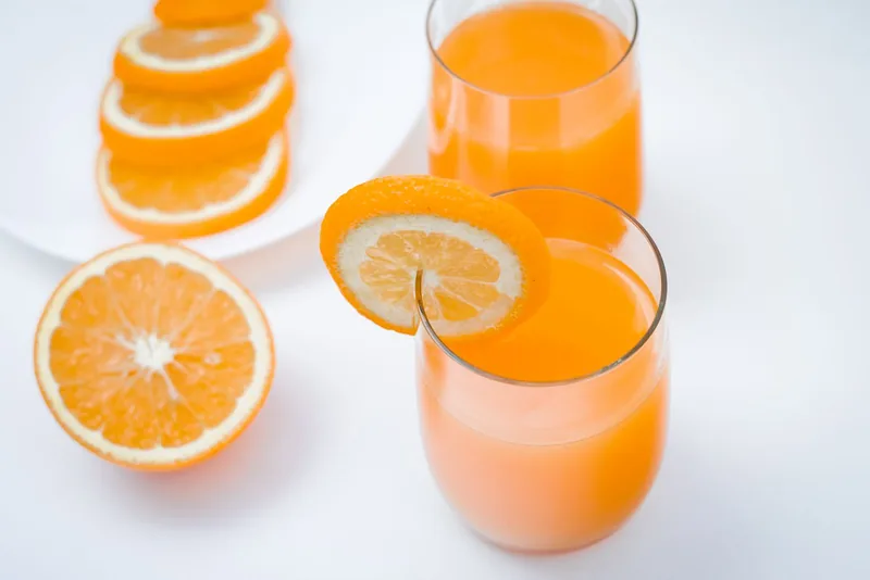 Verres de jus d’orange et agrumes frais dans une lumière naturelle. Photographie d’inspiration.